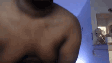 a man without a shirt is standing in a room with a blue wall .