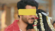 a man with a yellow blindfold on his eyes is kissing a woman