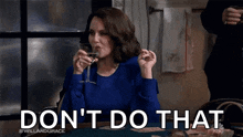 a woman is sitting at a table drinking a glass of wine and saying `` do n't do that '' .