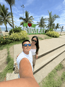 a man and woman are posing in front of a sign that says wow sipalay