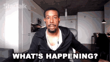 a man is sitting in front of a camera with the words what 's happening below him
