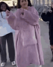 a woman in a pink coat is dancing with another woman .