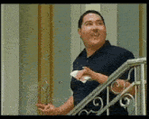 a man in a blue shirt is standing on a staircase holding a piece of paper