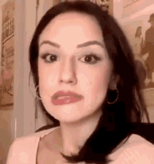 a close up of a woman 's face with a pink shirt and hoop earrings .