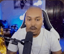 a bald man with a beard is sitting in front of a microphone while wearing headphones .
