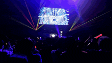 a crowd of people at a concert watching a dj