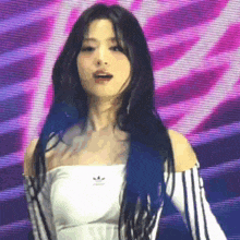 a woman with long black hair is wearing a white off the shoulder top and black and white striped sleeves .