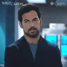 a man with a beard is standing in front of a gem sign