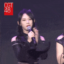 a woman with long black hair is holding a microphone in her hand