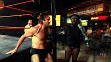 two wrestlers in a ring with a bud light sign in the background