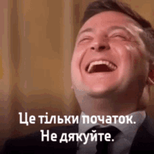a man in a suit and tie is laughing with a caption in another language .