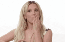 the woman is blowing a kiss with her hand .