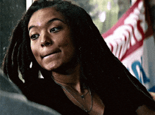 a woman with dreadlocks is smiling in front of a sign that says ' coca cola ' on it