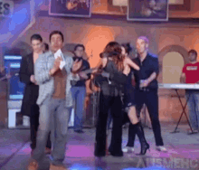 a group of people are dancing in front of a sign that says apsmehc on it