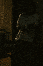 a man with his arms crossed is standing in a dark room