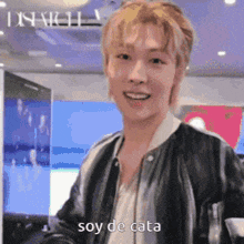 a man wearing a black jacket is smiling and says soy de cata