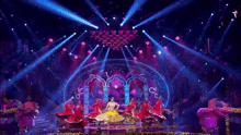 a group of dancers are performing on a stage with a lot of lights shining on them .
