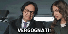 a man and a woman are sitting in a car and the man says " verognati "