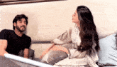 a man and a woman sitting on a couch talking to each other
