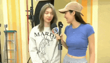 two women are standing next to each other holding microphones .