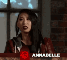 a woman in a red jacket stands in front of a banner that says annabelle