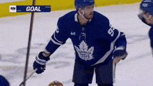 a hockey player in a toronto maple leafs jersey holds a stick