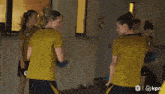 a woman in a yellow shirt with a lion on it is holding a blue soccer ball