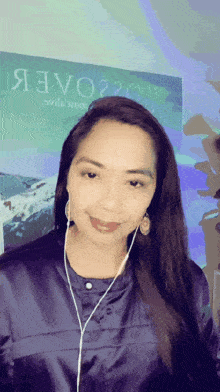 a woman wearing ear buds stands in front of a poster that says я3v020