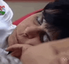 a close up of a person laying down with their eyes closed and their hand on their face .