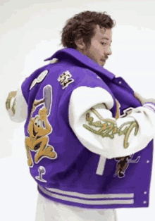 a man is wearing a purple varsity jacket with a picture of a monkey on the back
