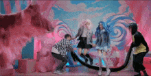 a group of people are dancing in front of a pink and blue background with lollipops