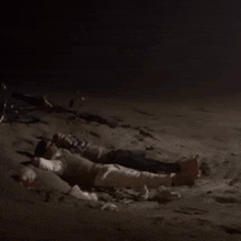 two people are laying on the sand at night