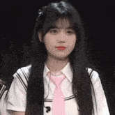 a girl with long black hair and a pink tie is wearing a school uniform .