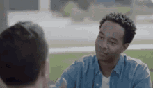 a man in a blue shirt is talking to another man in a white shirt .