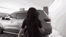 a woman in a black shirt is standing in front of a car that is made in animatica