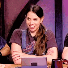 a woman wearing a harley davidson t-shirt smiles while sitting at a table
