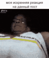 a man in a white tank top is laying down in a dark room .