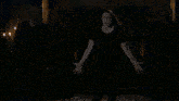 a crowd of people are dancing in a dark room with a blue light behind them .
