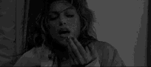 a black and white photo of a woman sticking her tongue out .