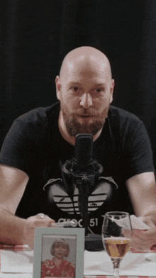 a bald man with a beard is sitting in front of a microphone with the number 51 on his shirt