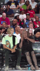a woman in a green shirt sits next to a man in a black shirt with the word crown royal on it