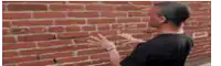 a man standing in front of a brick wall