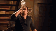 a man is drinking water from a bottle in a dark room