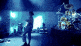 a man playing a guitar on a stage in front of a drum set