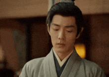 a man in a kimono is standing in a room looking down .