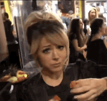 a woman in a black shirt is holding a slice of orange