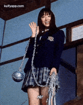 a woman in a school uniform is holding a chain and a rope .
