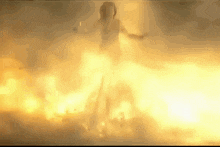 a silhouette of a person standing in front of a large fire