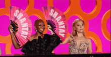 two women are holding fans that say shantay on them