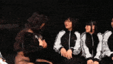 a group of women are standing around each other and one of them is wearing a rasho jacket